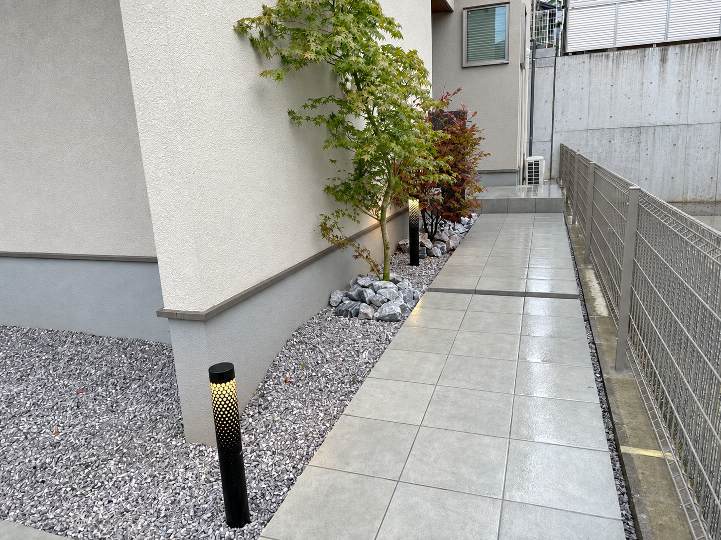 大判グレータイルと化粧砂利、植栽、ポールライトを組み合わせたロングアプローチ