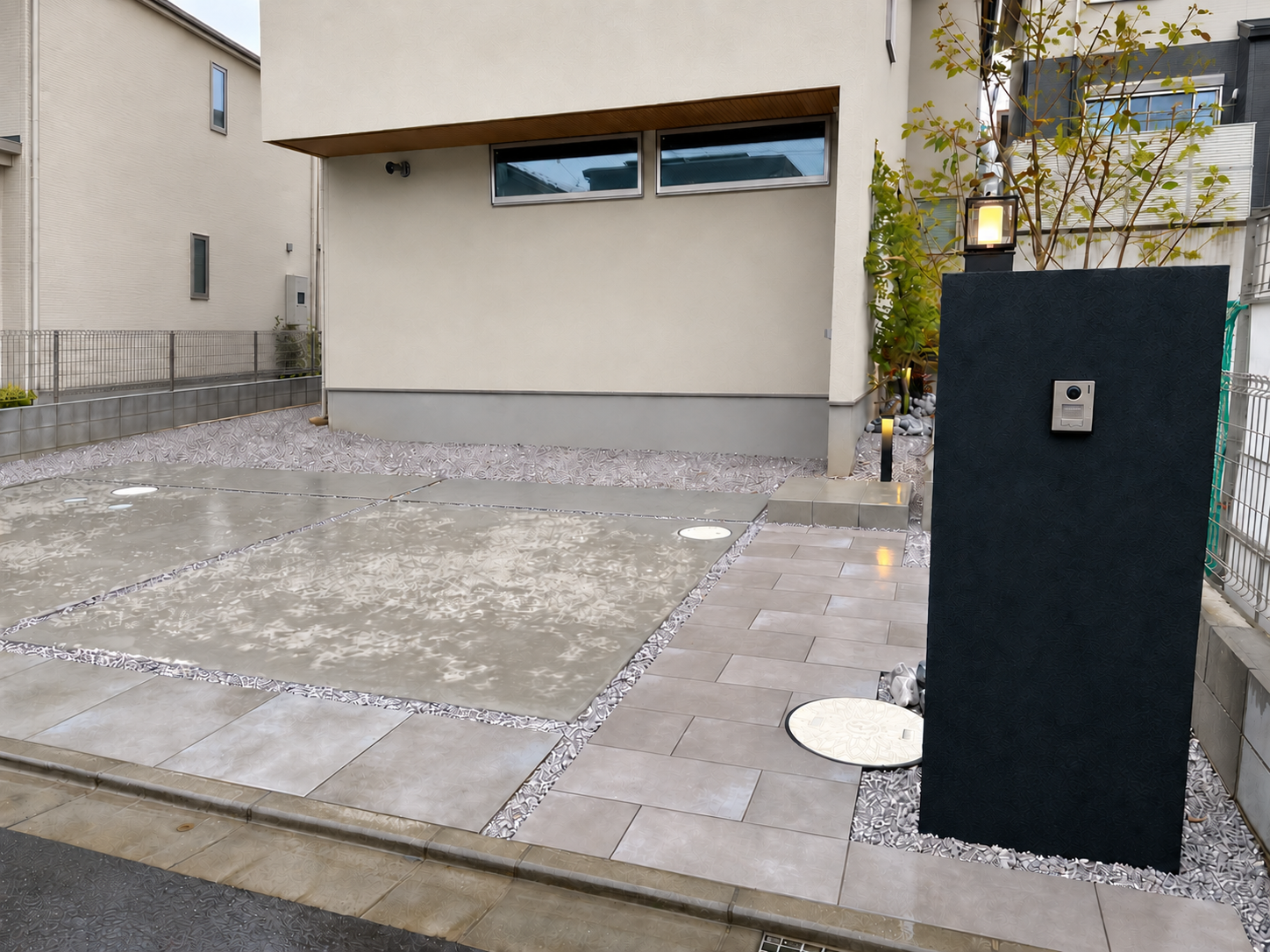 黒い塗り壁門柱と大判タイル、植栽を組み合わせた新築外構
